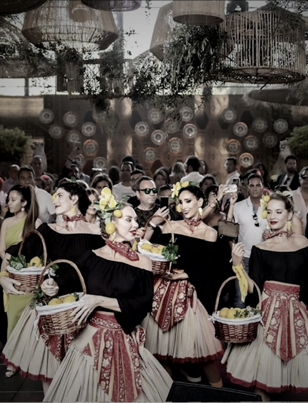 Grupo de performers com cestos de limões entre os convidados